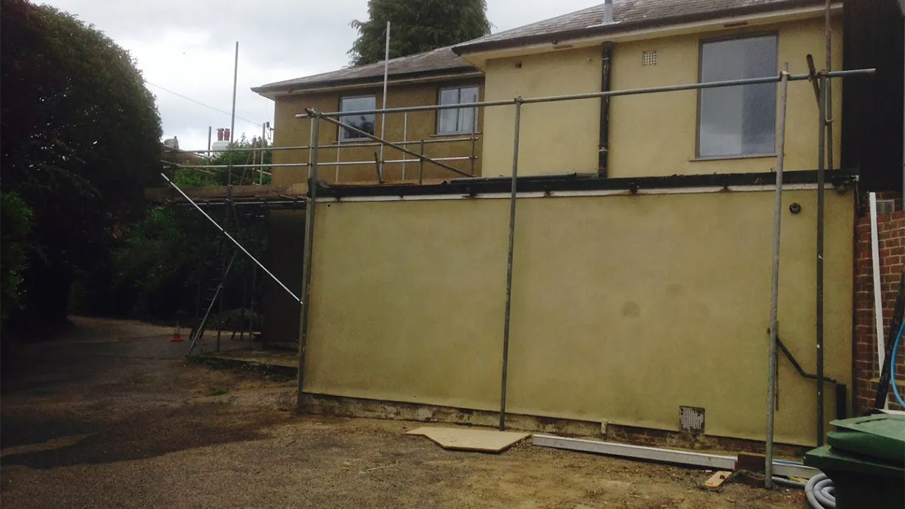 Two storey extension finished in coloured render with the scaffold still up, Surrey